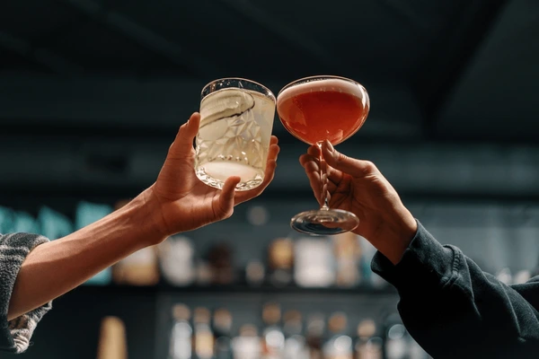 Two people hold cocktail glasses during a toast, leaving them to wonder if you can be charged with sexual assault if both parties were drunk.