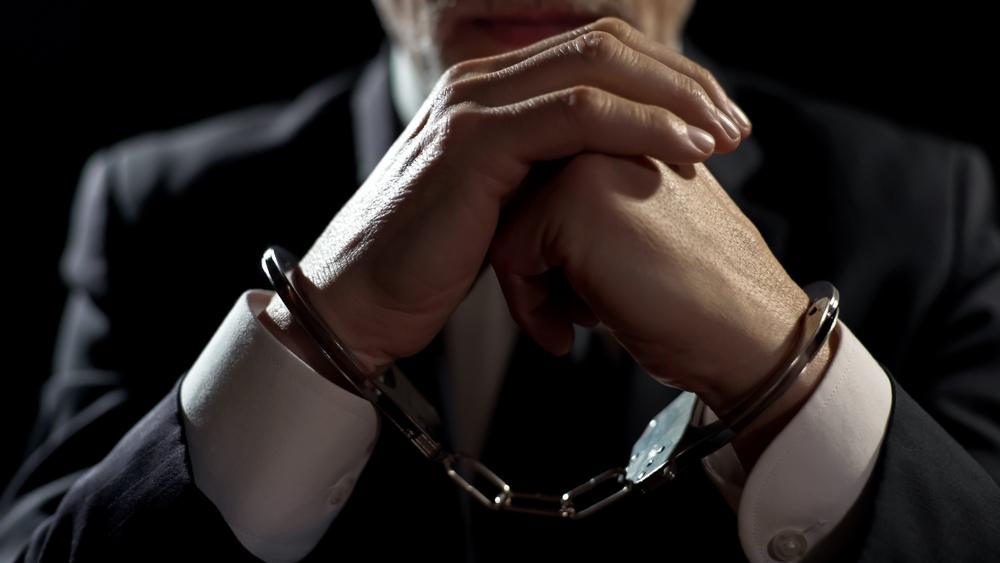 A man sits handcuffed after learning he's facing embezzlement charges. If you're accused of embezzlement, contact an embezzlement defense lawyer who understands how Ohio courts handle this serious theft offense.