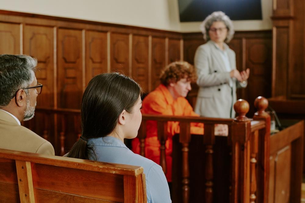 Teenage boy sitting in the defendant’s box in a courtroom, with the teen’s attorney detailing the Romeo and Juliet law in Ohio and how it applies to their client’s case