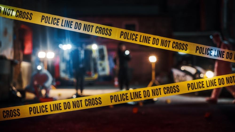 Crime Scene at Night: Crime Scene Investigation Team Working on a Murder. Female Police Officer Briefing Detective on the Victim's Body. Forensics and Paramedics Working.